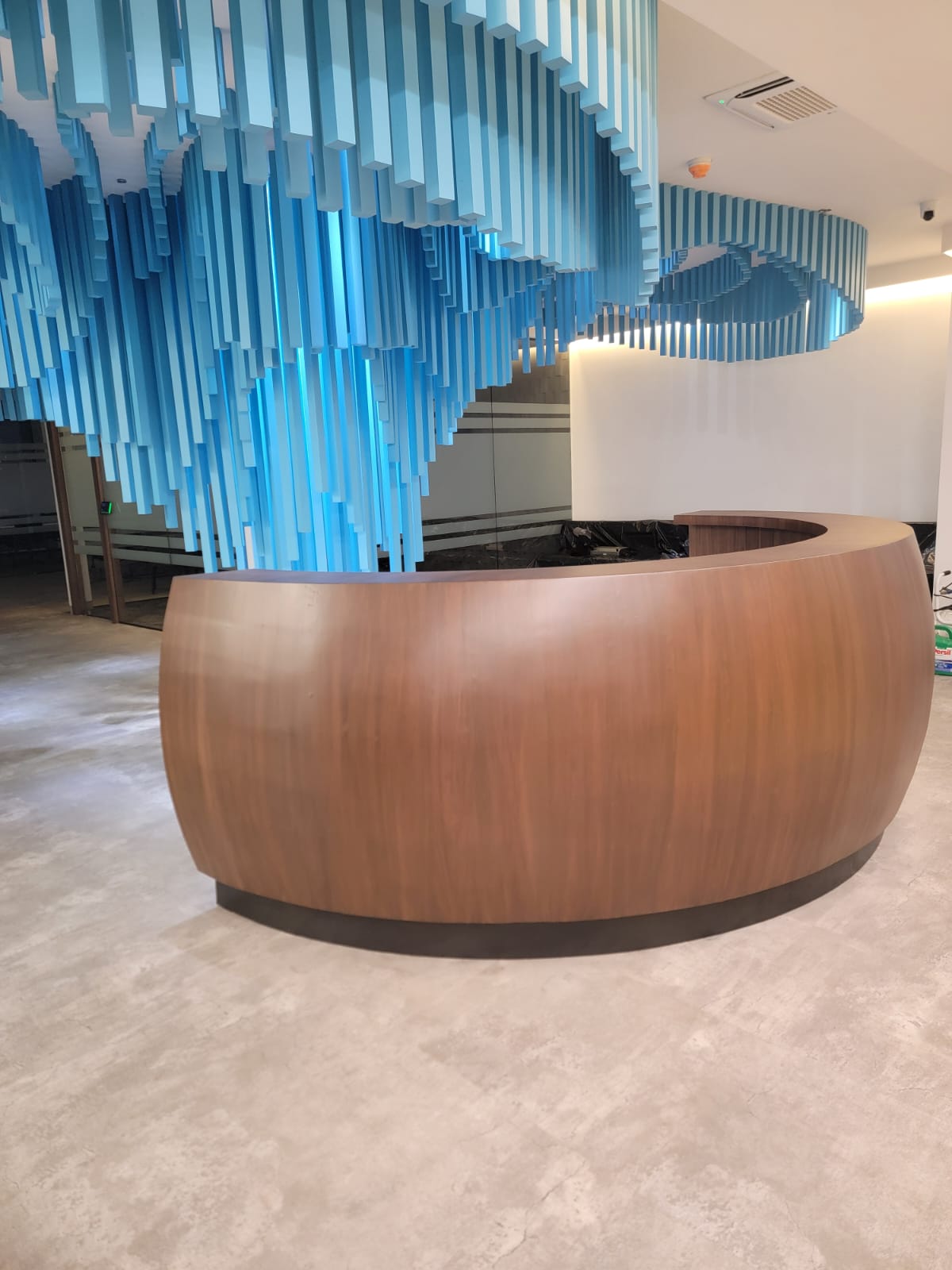 Recepción curva de madera a medida con instalación decorativa en techo